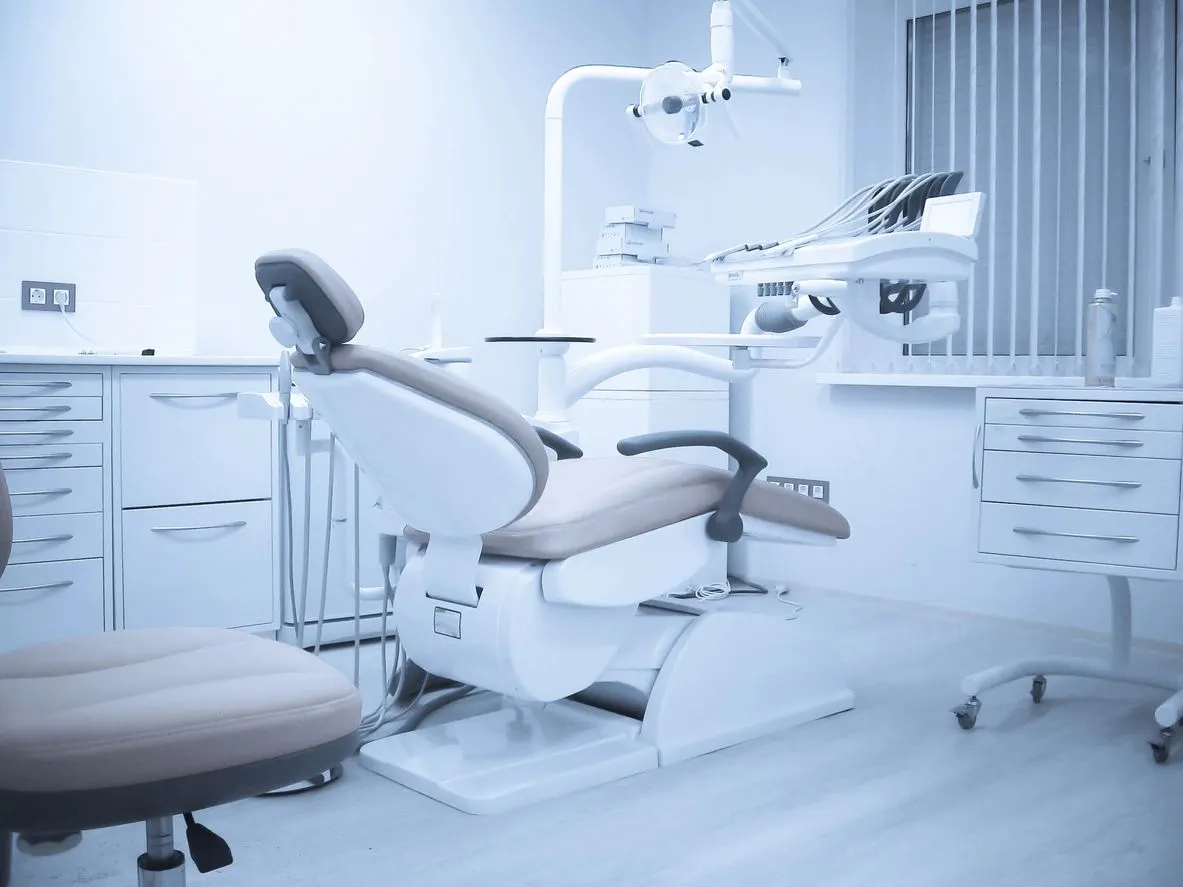 A dentist 's office with an empty chair and dental equipment.